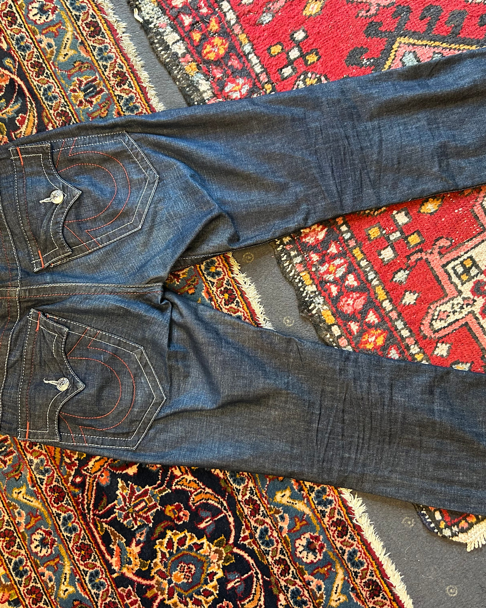 Jeans mit charakteristischer Gesäßtaschen-Naht, ausgebreitet auf Teppichen im Laden